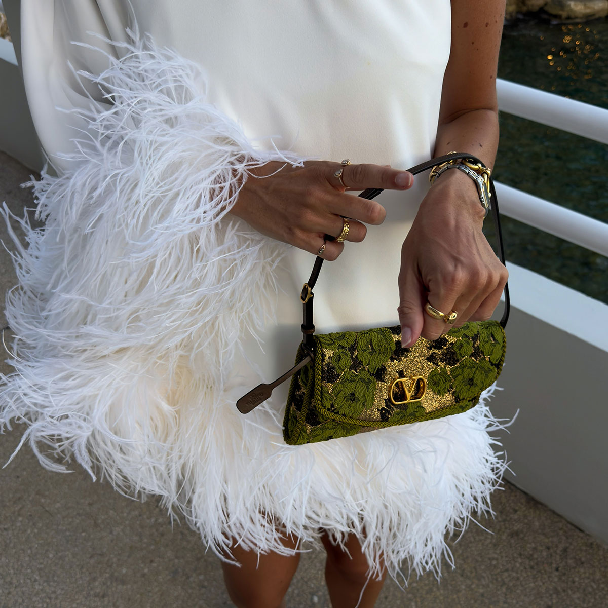 @juliesfi closeup photo in white feather-trimmed dress and valentino green jacquard printed shoulder bag