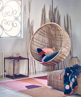 A bohemian bedroom with a rattan hanging seat and a colorful rug