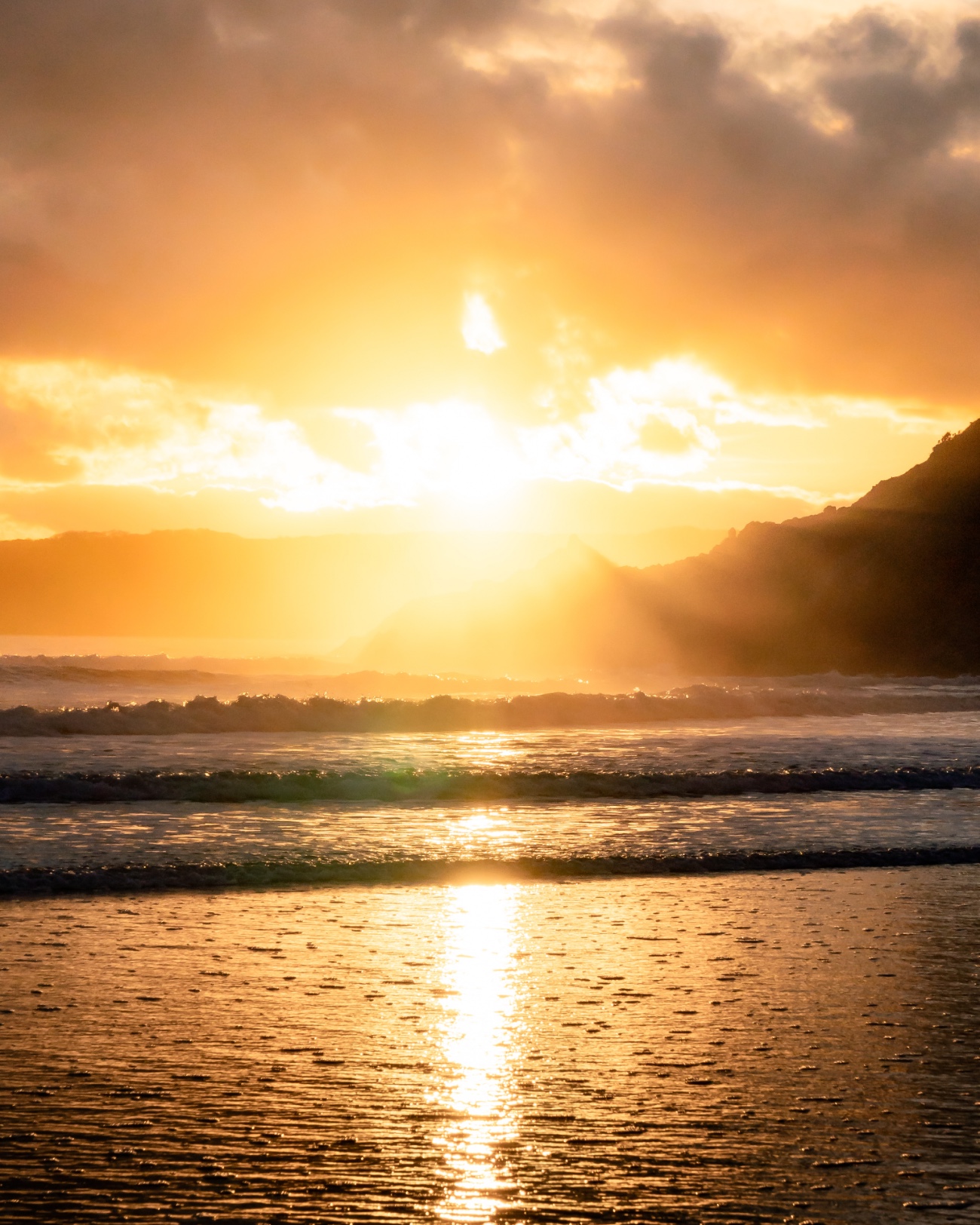 صورة للشاطئ عند غروب الشمس مع موجات لطيفة تستحم جميعها في وهج ذهبي.