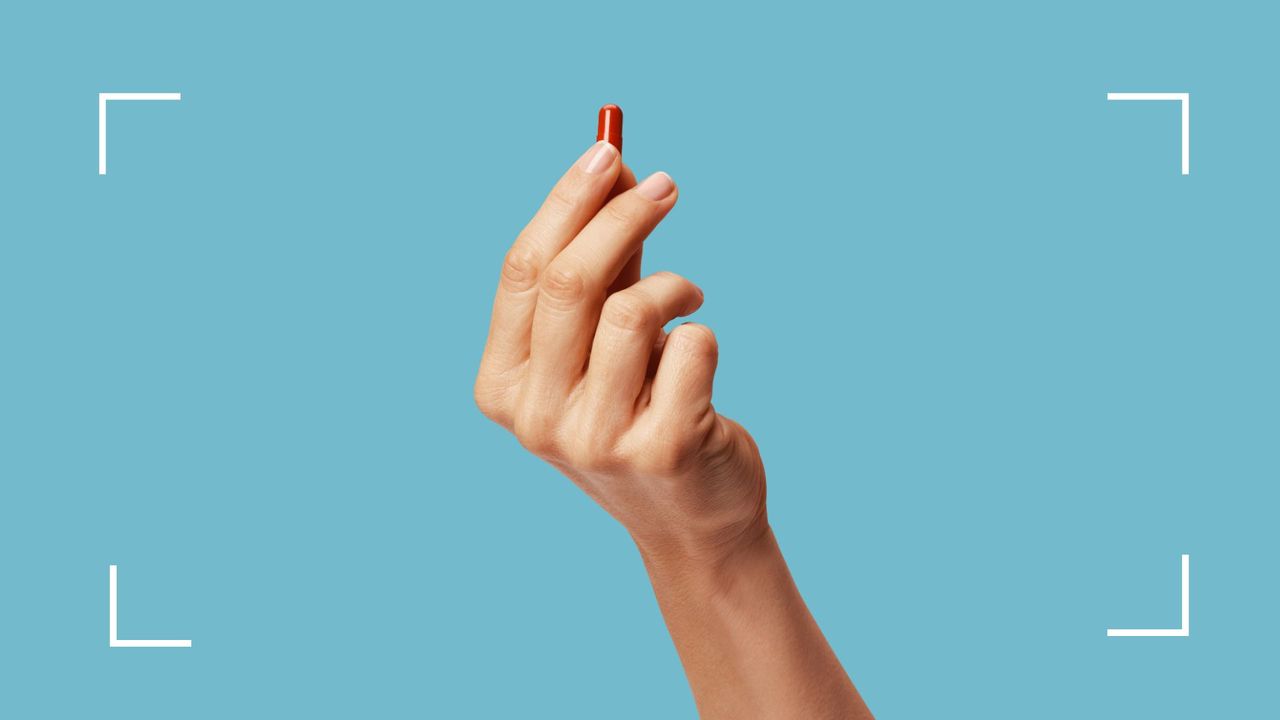 Woman&#039;s hand holding up a pill, representing Veoza, the new drug for hot flushes just approved in the UK 