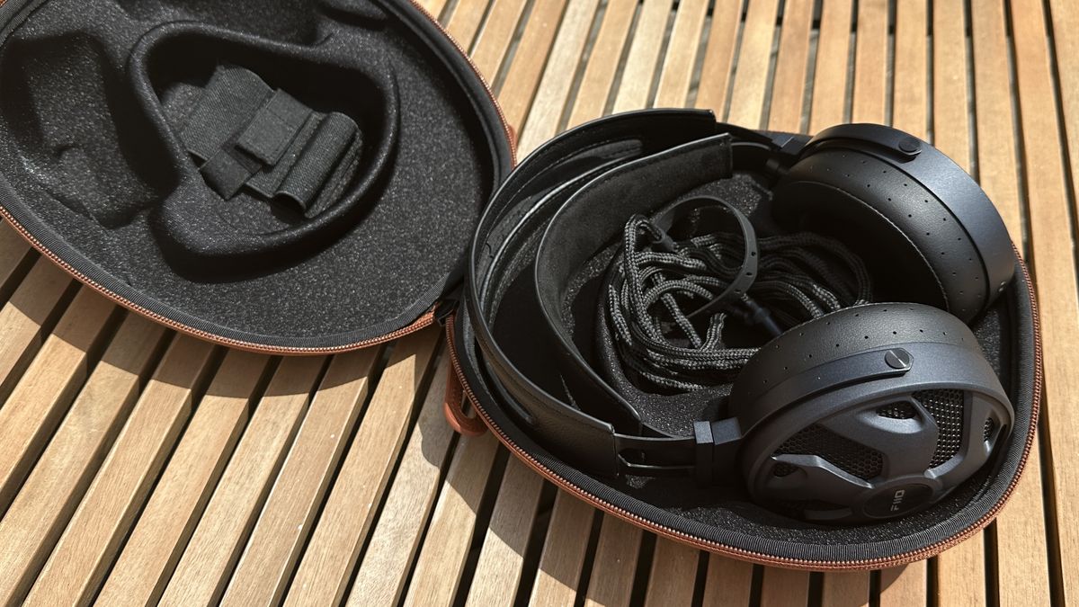 The FiiO FT3 over-ear headphones in their charging case against a wooden surface.
