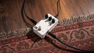 A JHS 3 Series Reverb pedal on a rug with guitar and power cables plugged in
