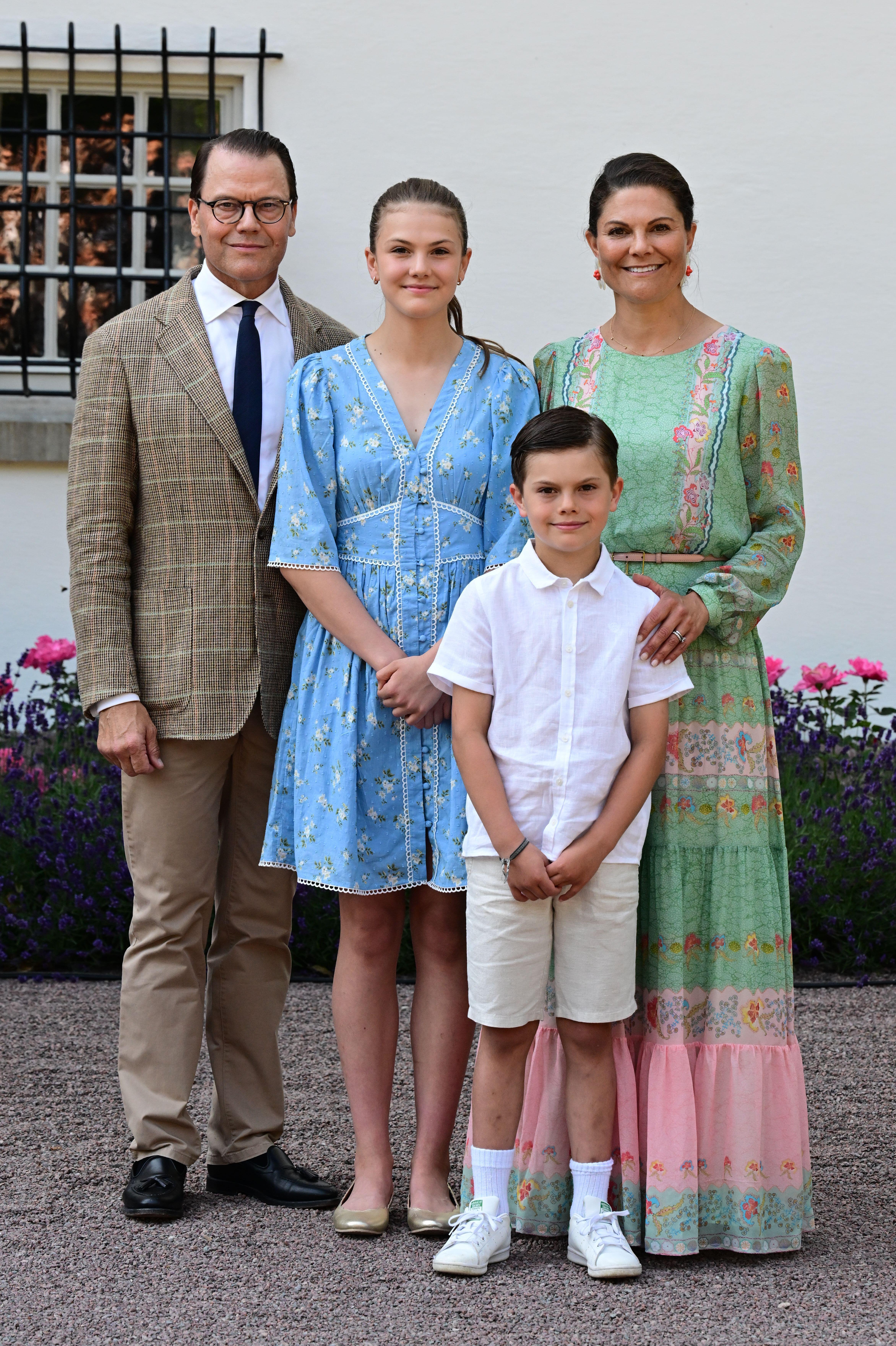 Prince Daniel, Princess Estelle, Prince Oscar and Crown Princess Victoria posing in front of flowers on Victoria's birthday
