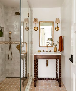 A rustic bathroom with a wooden pedestal sink beside a glass shower door.