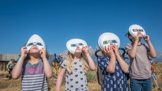 Group of children look up wearing eclipse glasses to watch Solar Eclipse, Grand Tetons National Park, Teton County, Wyoming