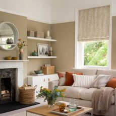 Neutral living room with rug, fireplace, coffee table, sofa and blind on window