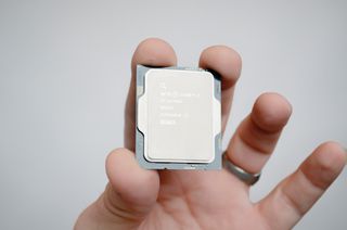 A masculine hand holding an Intel Core i7-14700K