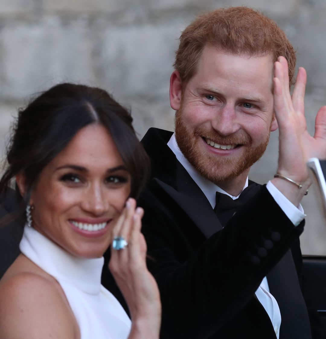 Prince Harry and Meghan Markle waving while driving to their wedding reception in a convertible