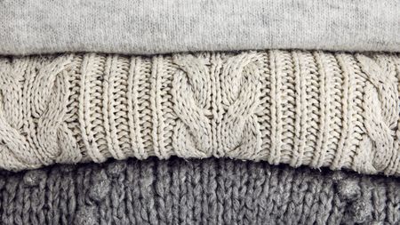 Close-up of three folded gray wool sweaters stacked