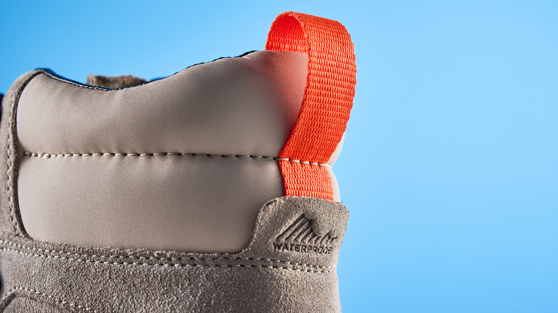 The Columbia Newton Alpine rear pull tab on a stone surface with a blue background