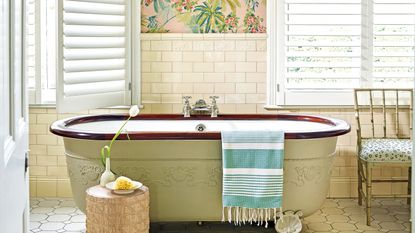 freestanding bathtub against wall with patterned wallpaper and large windows with venetian blinds
