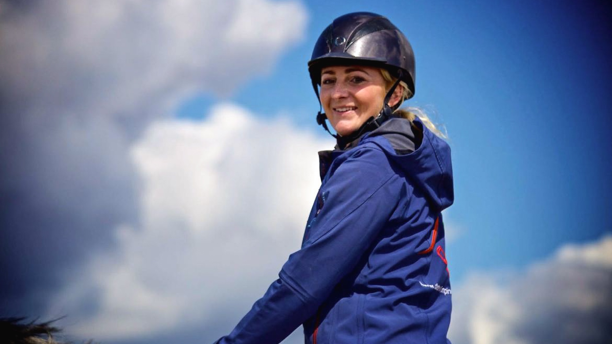 A smiling Lola Wade riding a horse