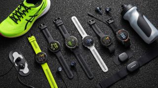A collage featuring eight Garmin smartwatches lying on a black mat next to some earbuds, trainers and a water bottle.