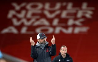 Liverpool Jurgen Klopp points two fingers to the sky in front of a You'll Never Walk Alone banner on the Kop