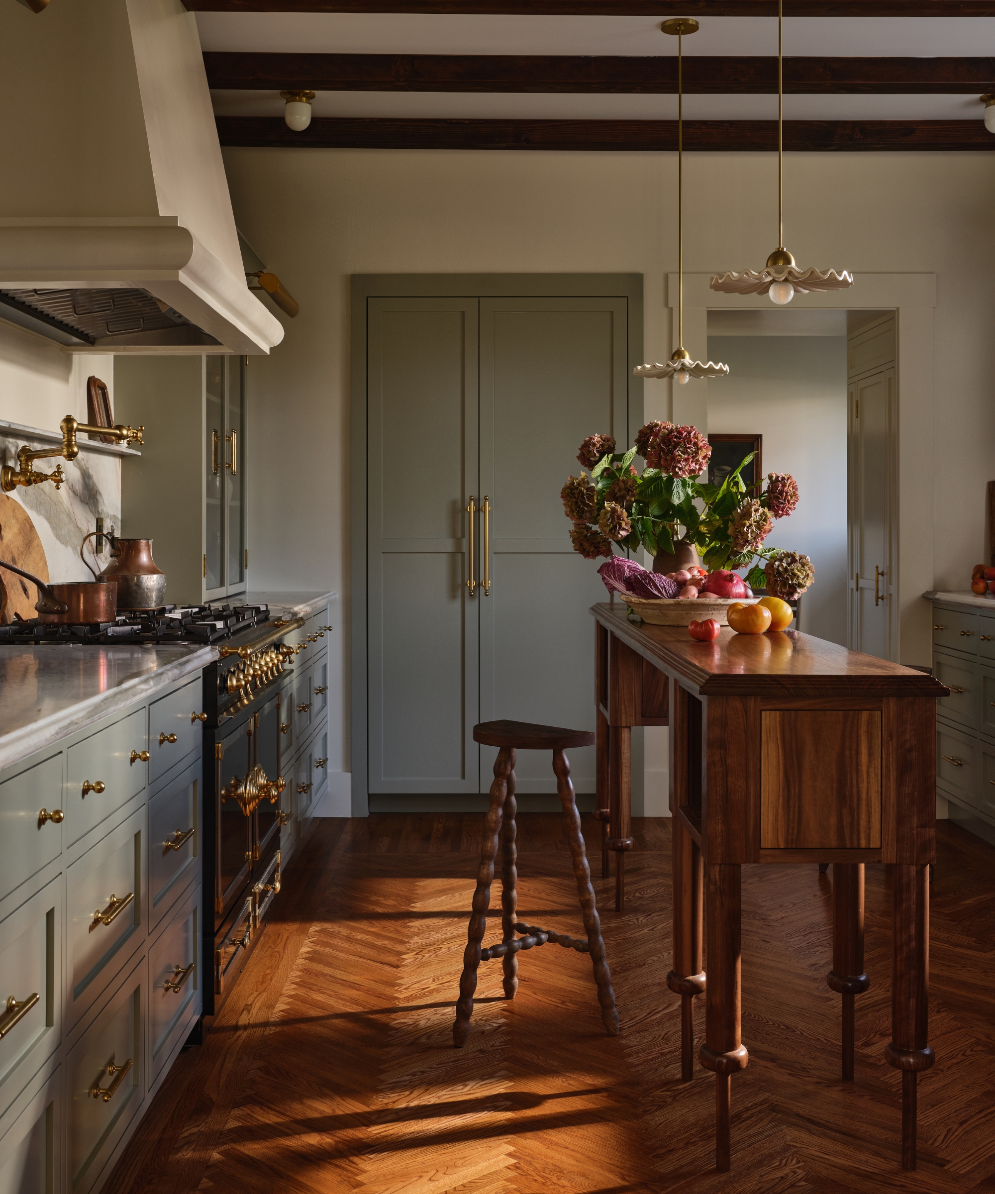 A small kitchen with pale blue cabinets, warm white walls, and a custom narrow wooden island