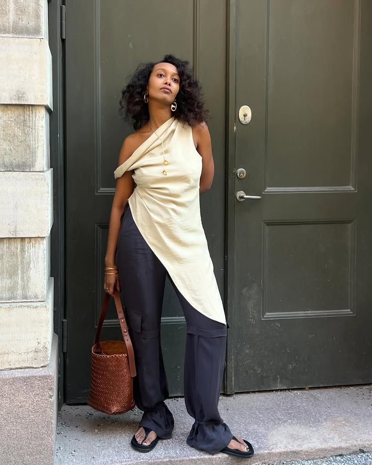 @monamali_ wears an asymmetric top with navy wide-leg trousers and sandals