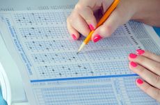 a student with neon pink nails taking a standardized test