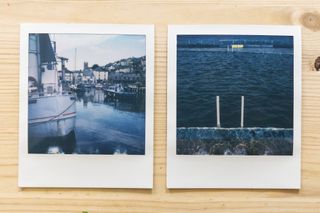 Two Polaroid SX-70 prints flat lay on a wooden table, one of a tidal pool another of a seaside harbour