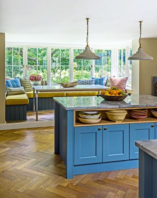 kitchen with blue island and window seat in bay window with wooden floor