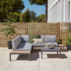 Grey corner sofa in garden with slatted fence