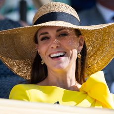 Kate Middleton wearing a yellow dress and sun hat smiling 