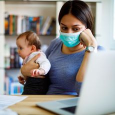 Unemployed woman wearing face mask holding her baby