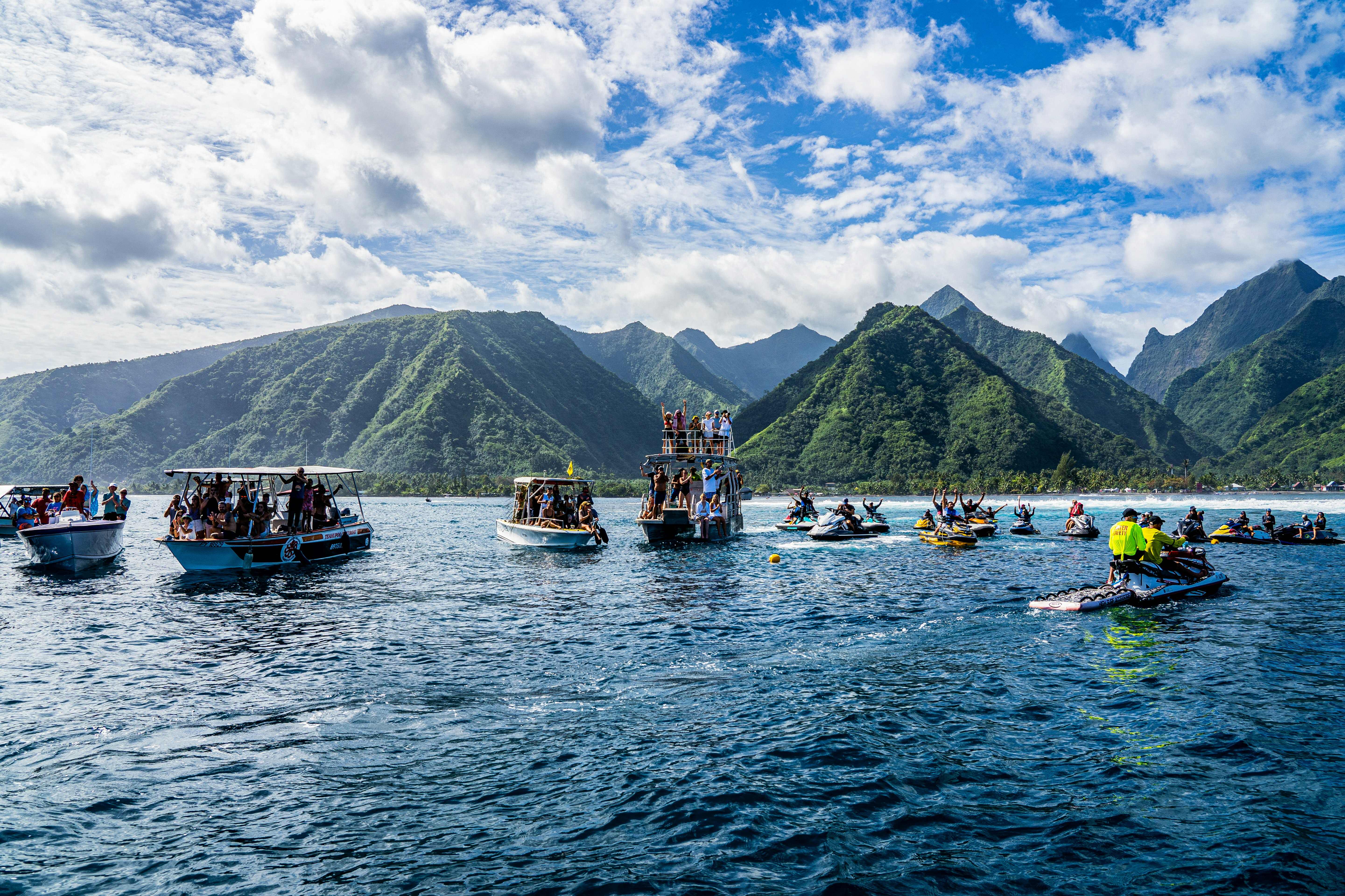 Spectators on boats watch surfers compete in Teahup'o, Tahiti