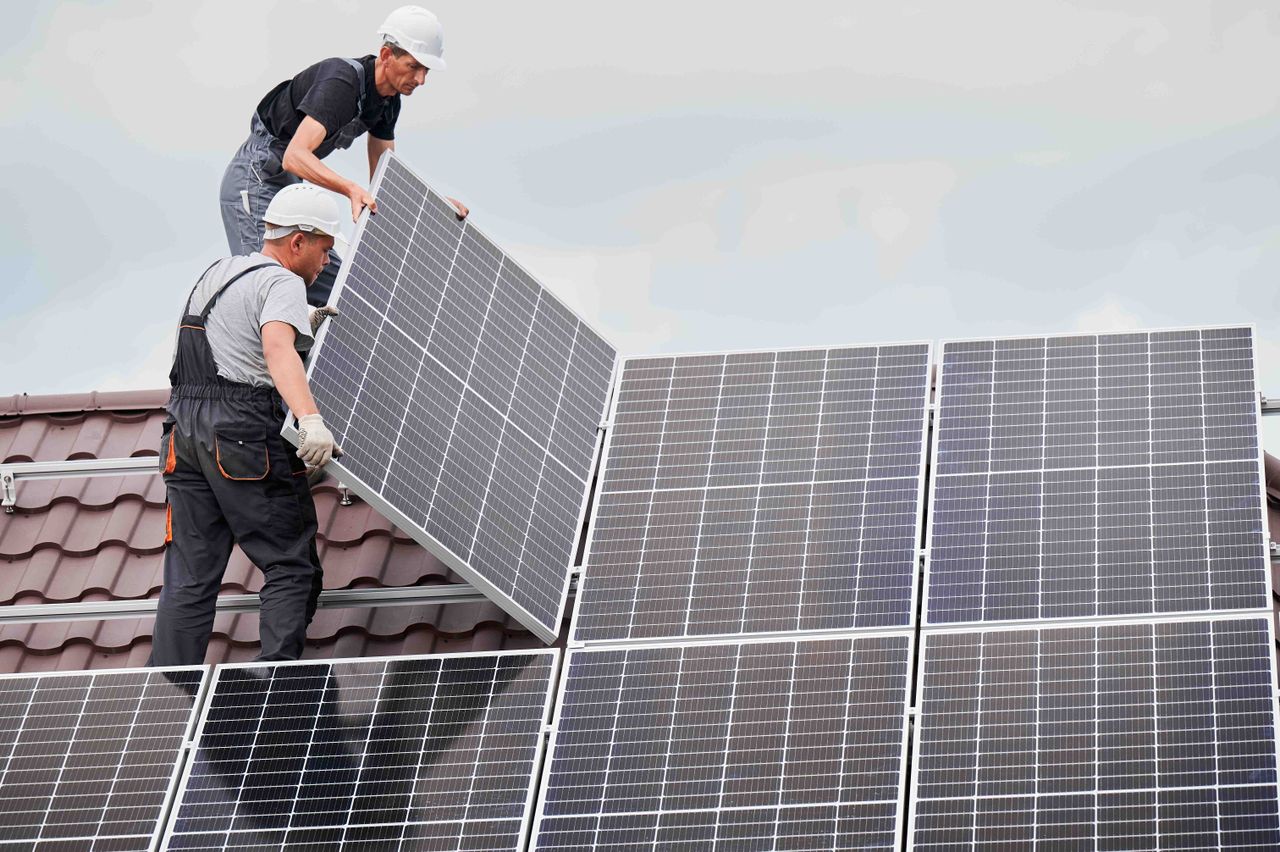 workers installing solar panels on a roof