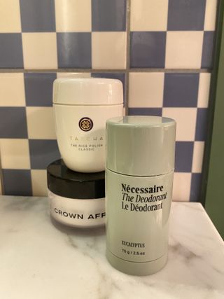 a stack of beauty products in Halie LeSavage's Copenhagen hotel room, including Necessaire deodorant