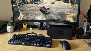 Nintendo Switch connected to mouse and keyboard with dock sitting on desk next to curved Samsung monitor.