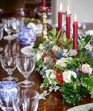 Christmas dining table with foliage, red candles, glassware