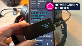 A smartphone screen with a DAC in front of it, showing LDAC playing. The DAC is held in a hand, with headphones in the background