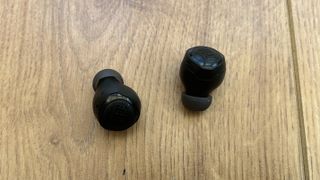 JBL Quantum TWS Air earbuds on a wooden surface