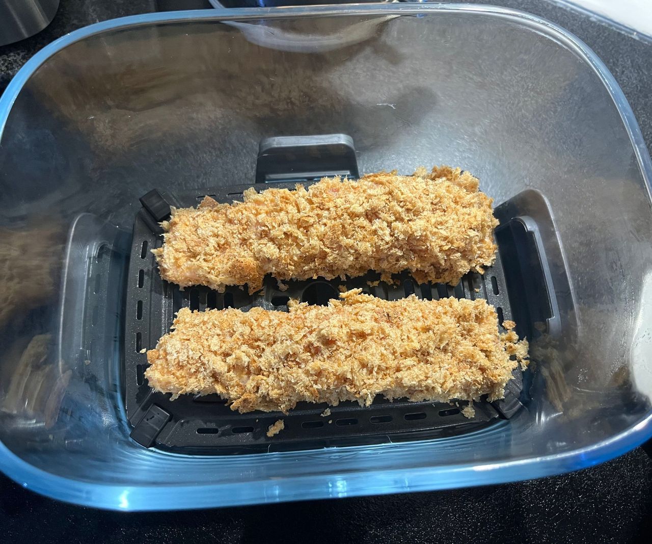 Two breaded salon fillets in a glass air fryer basket
