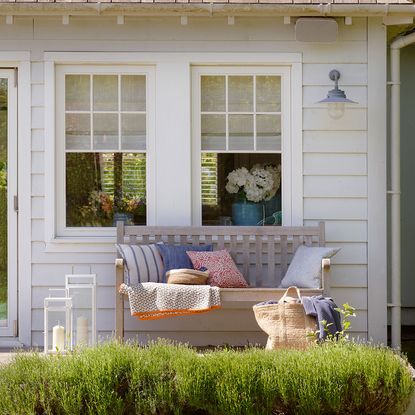 wooden bench with cushions and grass with candle lantern