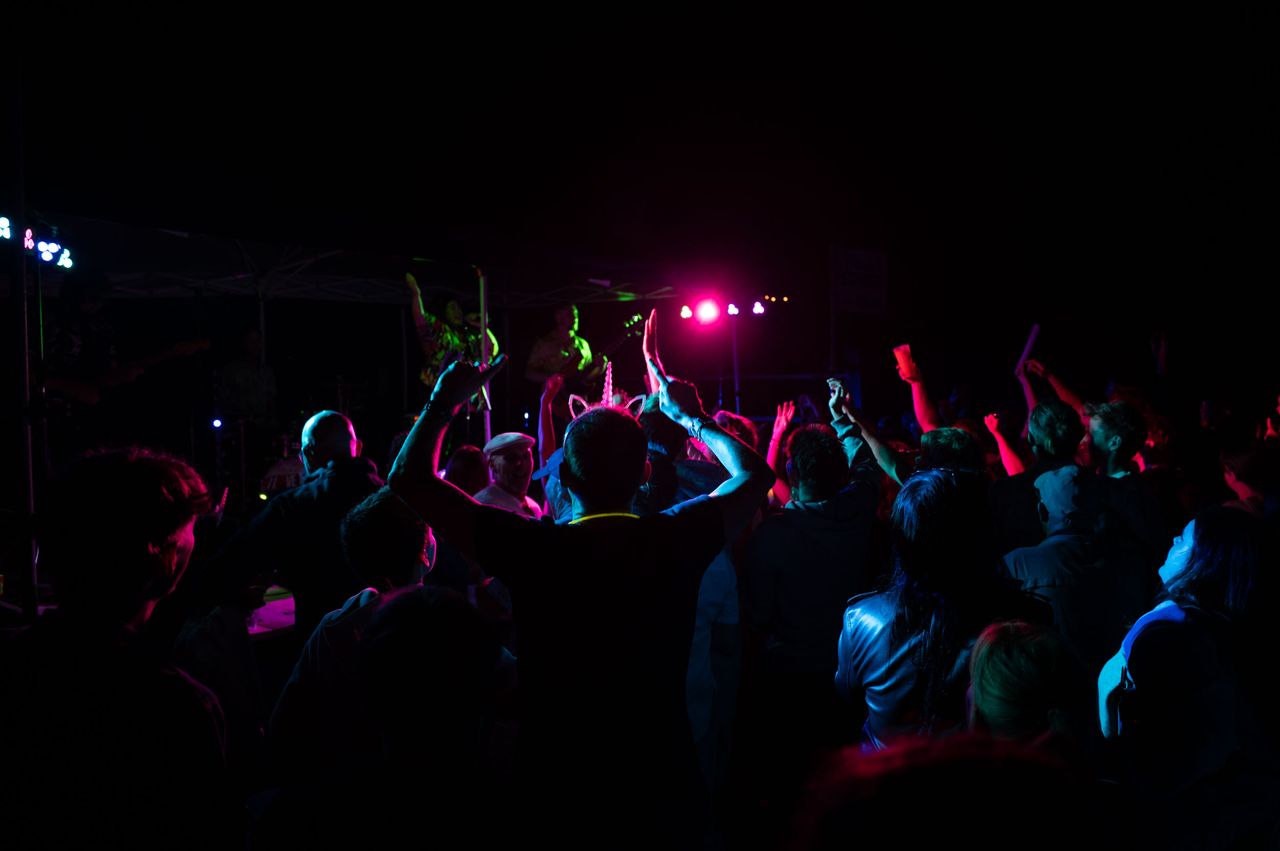 Revellers at a late night gig, illuminated by the multi-color stage lighting