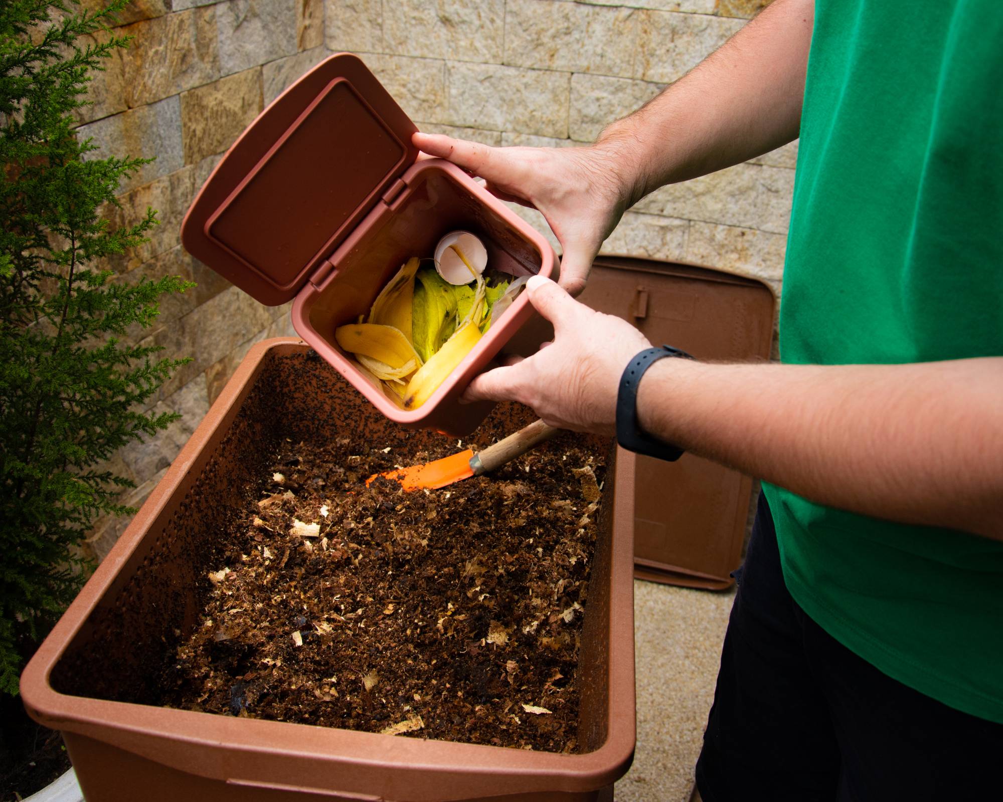 Gardener adding scraps to vermicomposting bin
