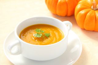 A pumpkin and a bowl of pumpkin soup