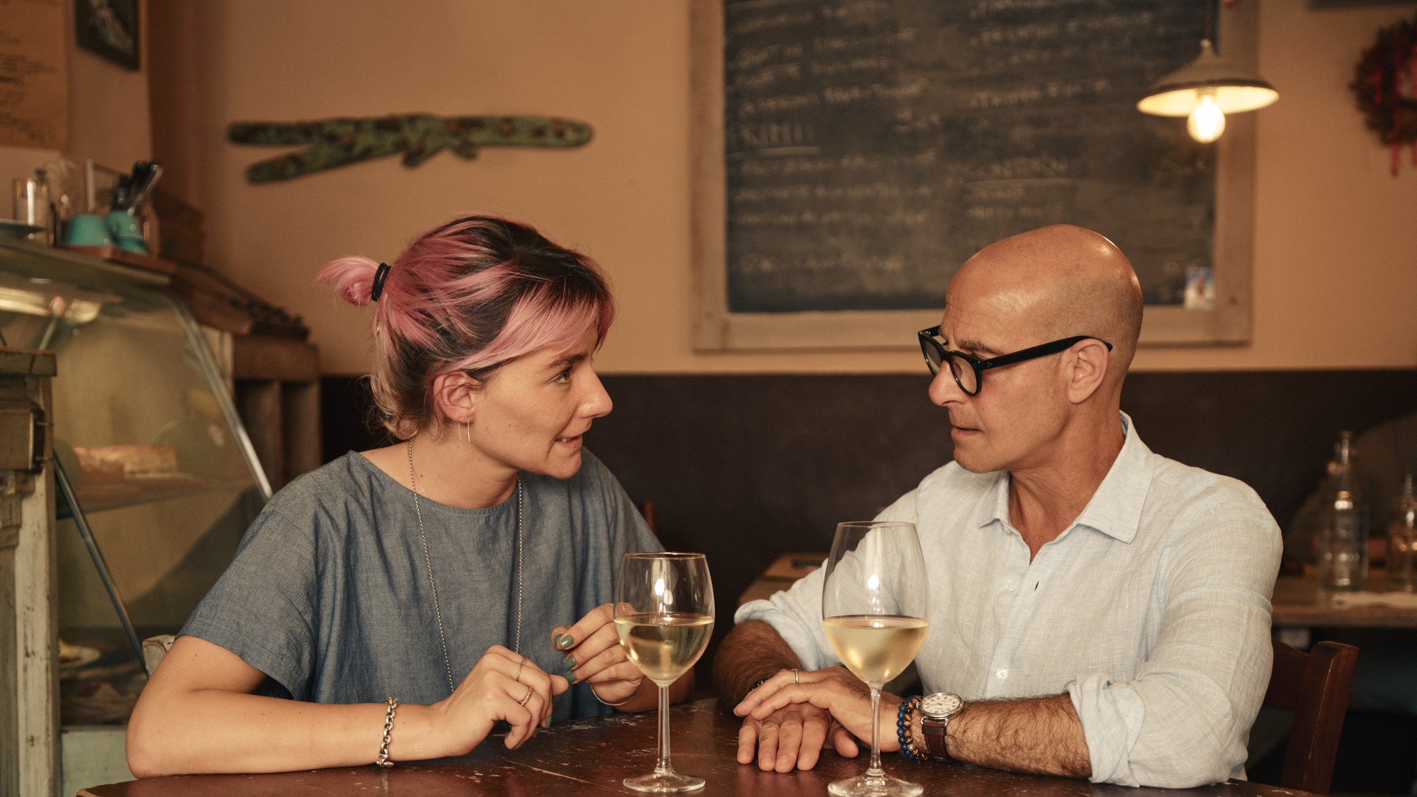 Matilde Pettini and Stanley Tucci sitting at a table in Tucci in Italy