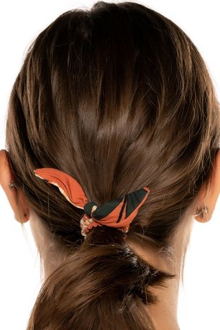 The back of a woman's head with a bun tied with a scarf