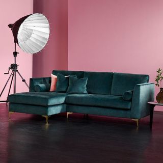 living room with pink wall green sofa and wooden flooring