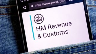 HMRC logo appearing on a smartphone which is nestled in the pocket of someone's jeans