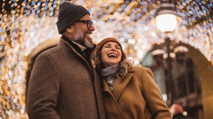 Laughing and smiling couple in their 50s standing together under lights