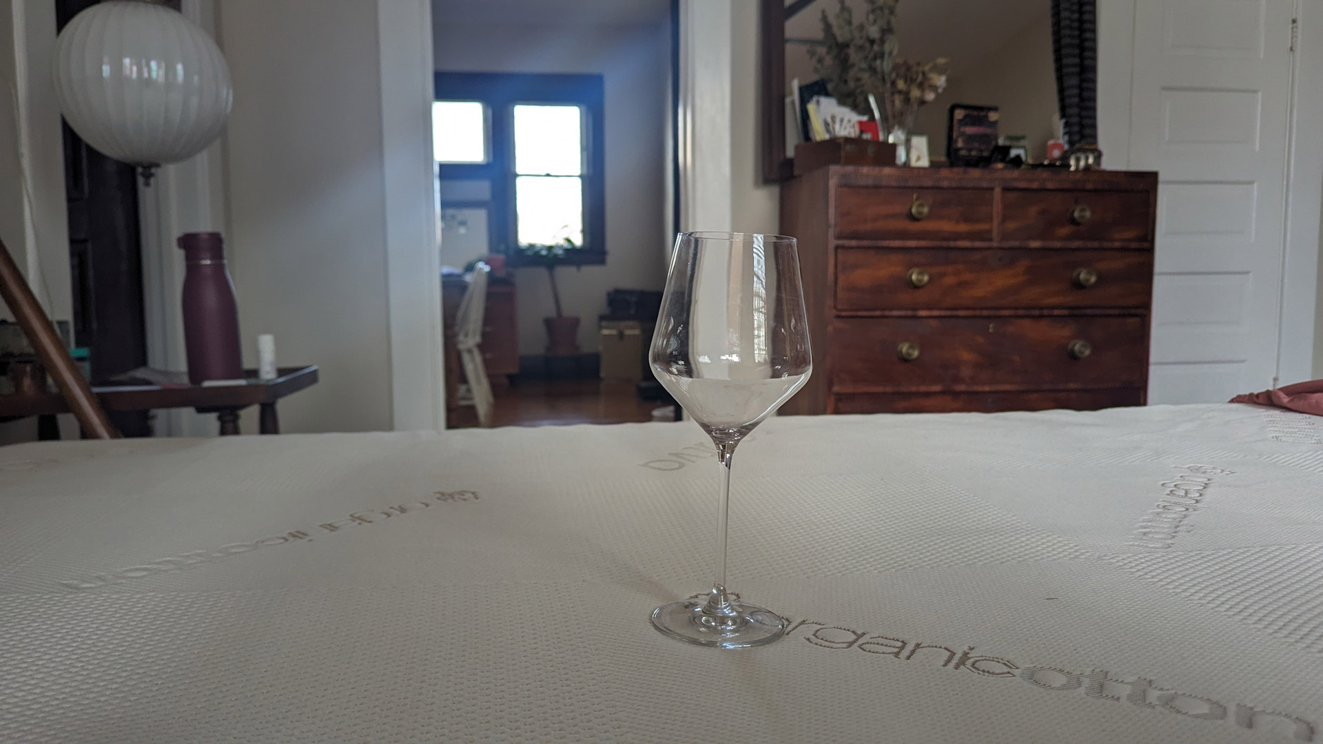 A wine glass on the Saatva Graphite Memory Foam Mattress Topper