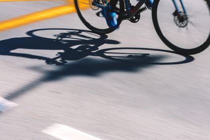 A cyclist rides on a sunny tarmac street