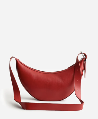 a Madewell red crescent bag in front of a plain backdrop