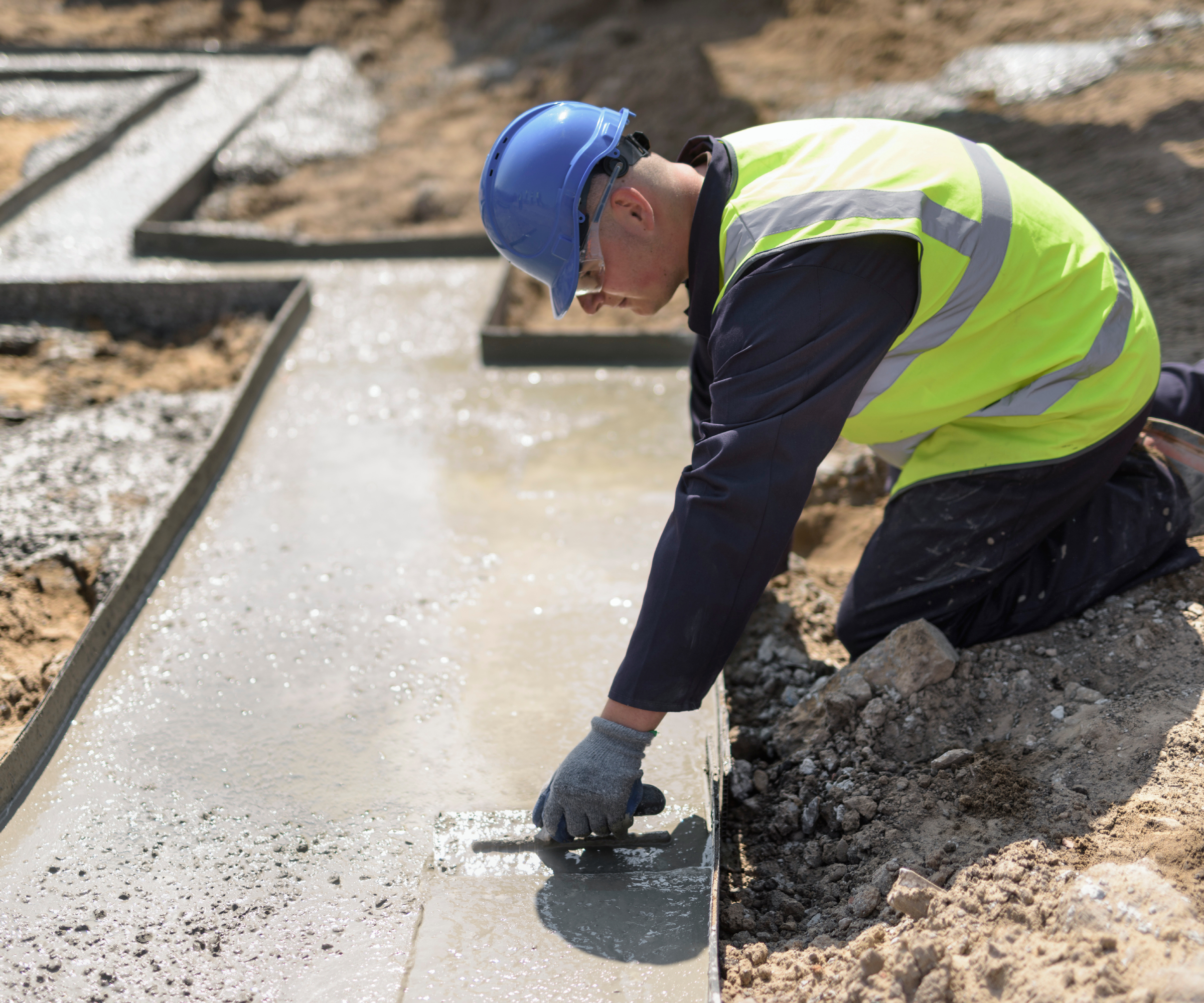 groundworker levelling concrete that's been poured into foundations