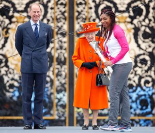 Prince Edward, Earl of Wessex (Vice-Patron of the Commonwealth Games Federation) and Queen Elizabeth II (Patron of the Commonwealth Games Federation) look on as Kadeena Cox carries The Queen's Baton
