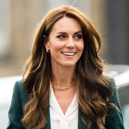 Catherine, Princess of Wales whilst visiting Leeds on September 26, 2023, in a green Burberry wool suit, white shirt and gold jewellery, smiling and looking away from the camera 