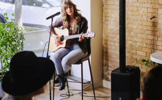 Woman playing guitar with the JBL PRX One